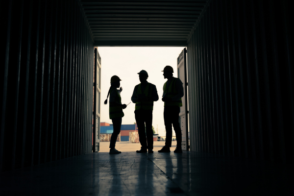 3 workers stand in a shipping container. One describes a customs fraud incident she's seen.