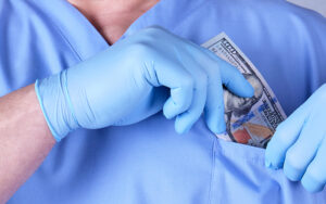 A surgeon pocketing money inside his coat.